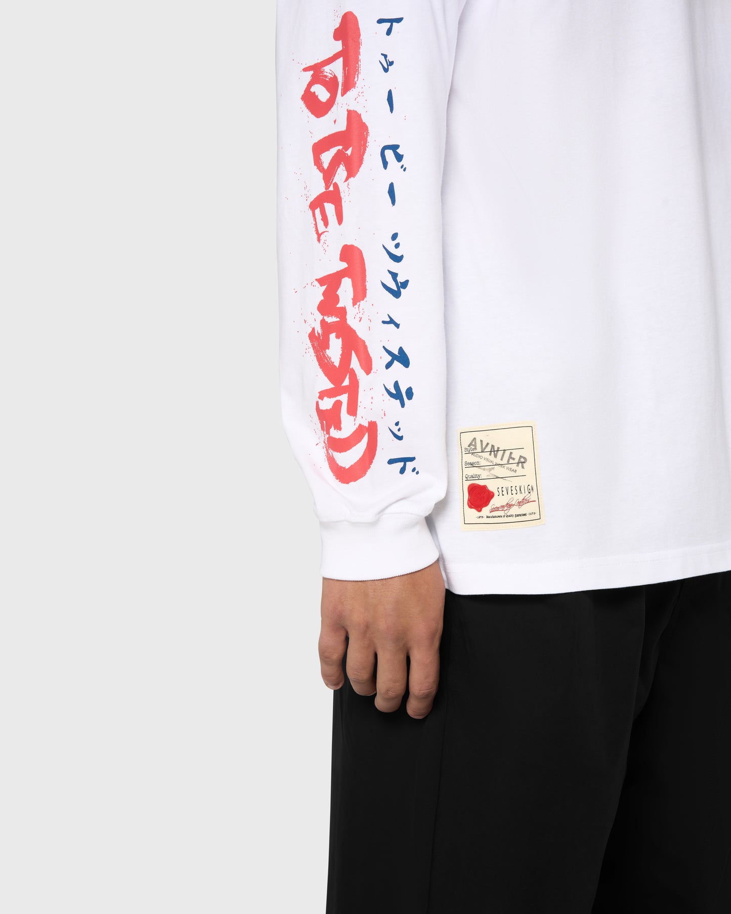 Zoom sur la manche du t-shirt blanc AVNIER × SEVESKIG, lettrage japonais rouge et bleu, collaboration franco-japonaise. - Blanc