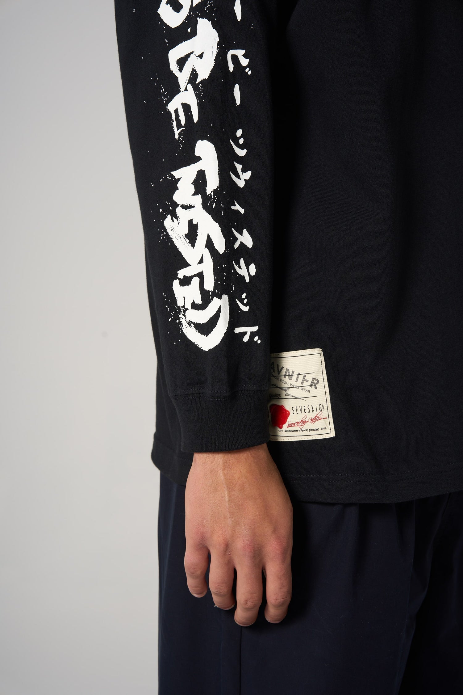Détail sur la manche du t-shirt noir AVNIER × SEVESKIG, lettrage graphique inspiré du style japonais. - noir