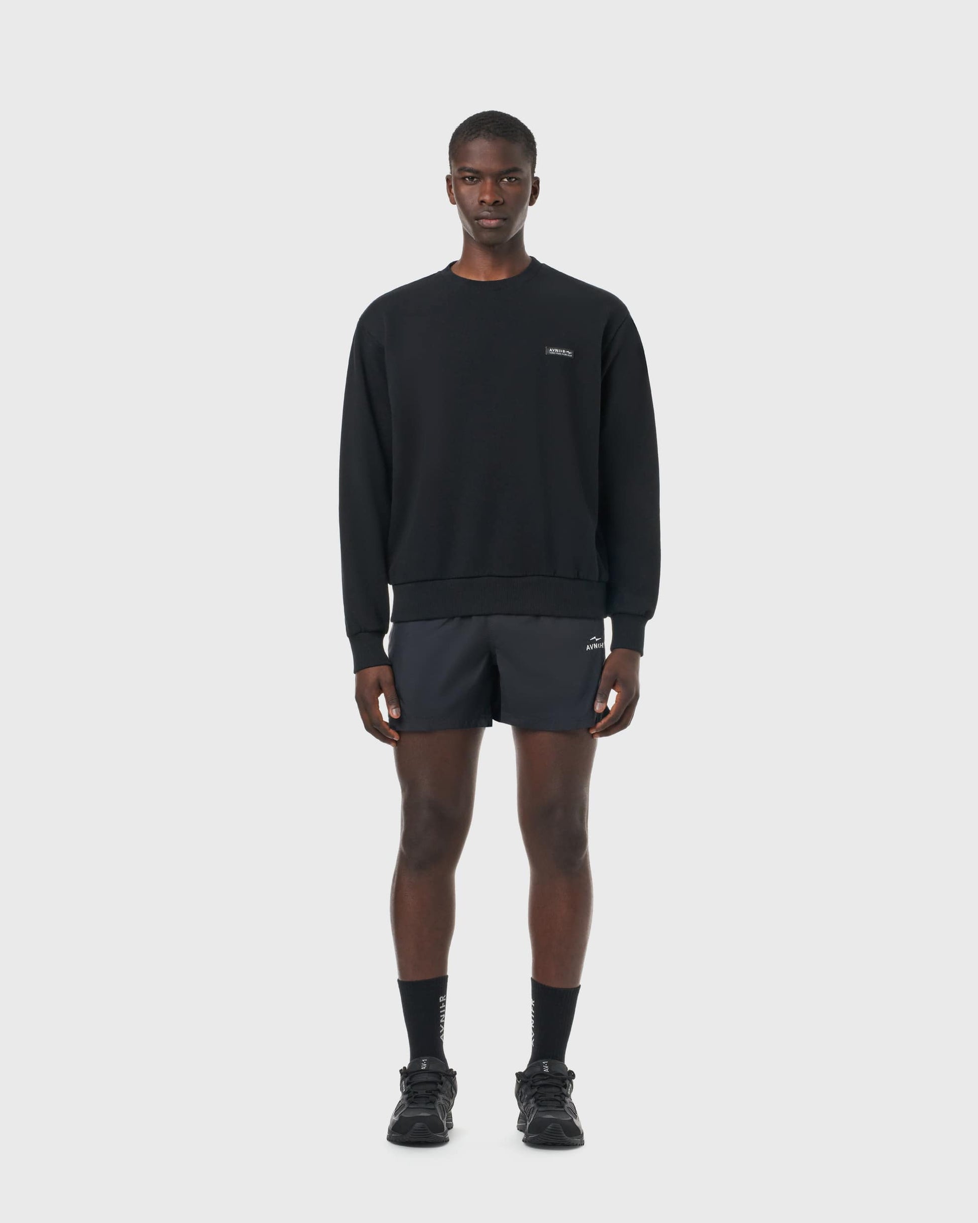 Sweat noir Avnier Encore V4 porté par un homme, coupe droite et style créatif minimaliste.
