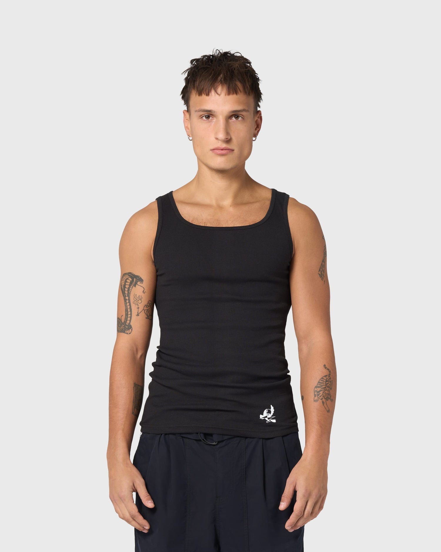 Débardeur noir AVNIER × TUCO, vue de face sur modèle, coupe cintrée en coton côtelé, logo contrasté discret.