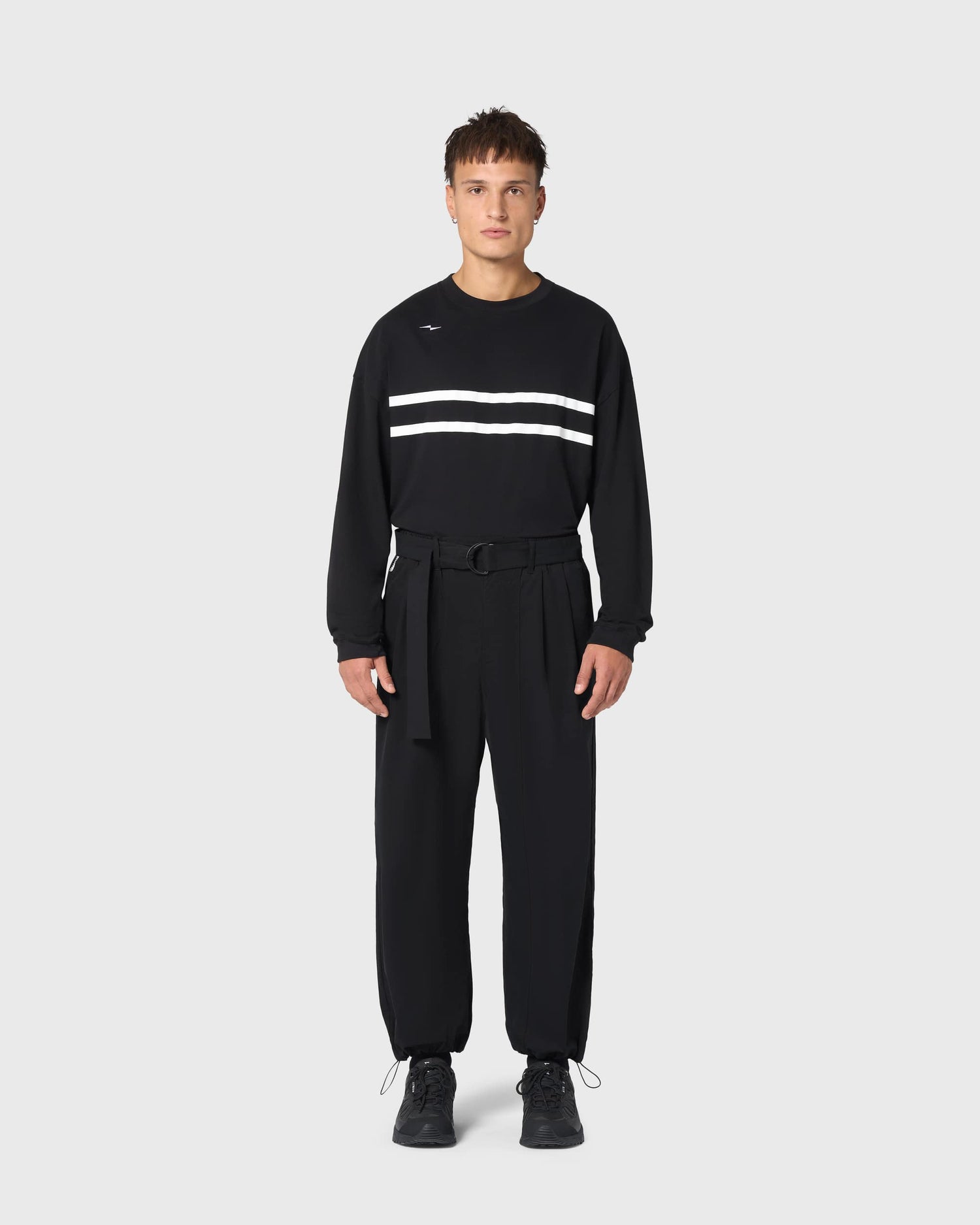 Pantalon Housaka AVNIER × Saint James noir porté de face, coupe oversize fluide et ceinture technique à boucle ajustable.