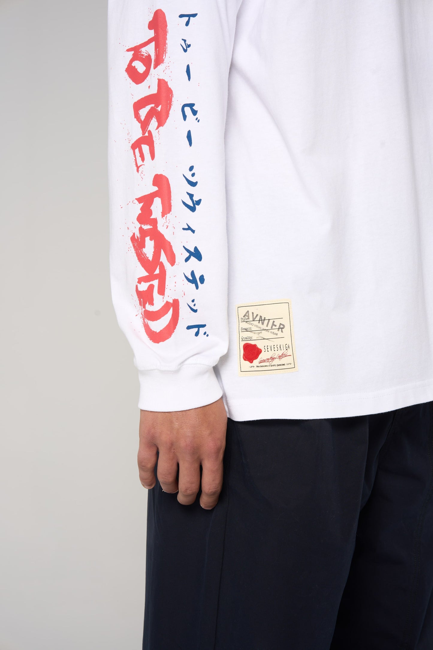 Détail sur la manche du t-shirt blanc AVNIER × SEVESKIG, lettrage japonais rouge et bleu, collaboration franco-japonaise. - blanc