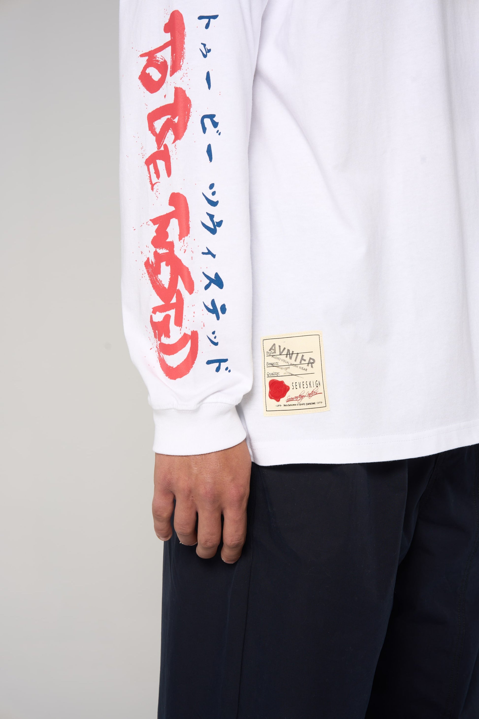 Détail sur la manche du t-shirt blanc AVNIER × SEVESKIG, lettrage japonais rouge et bleu, collaboration franco-japonaise. - blanc