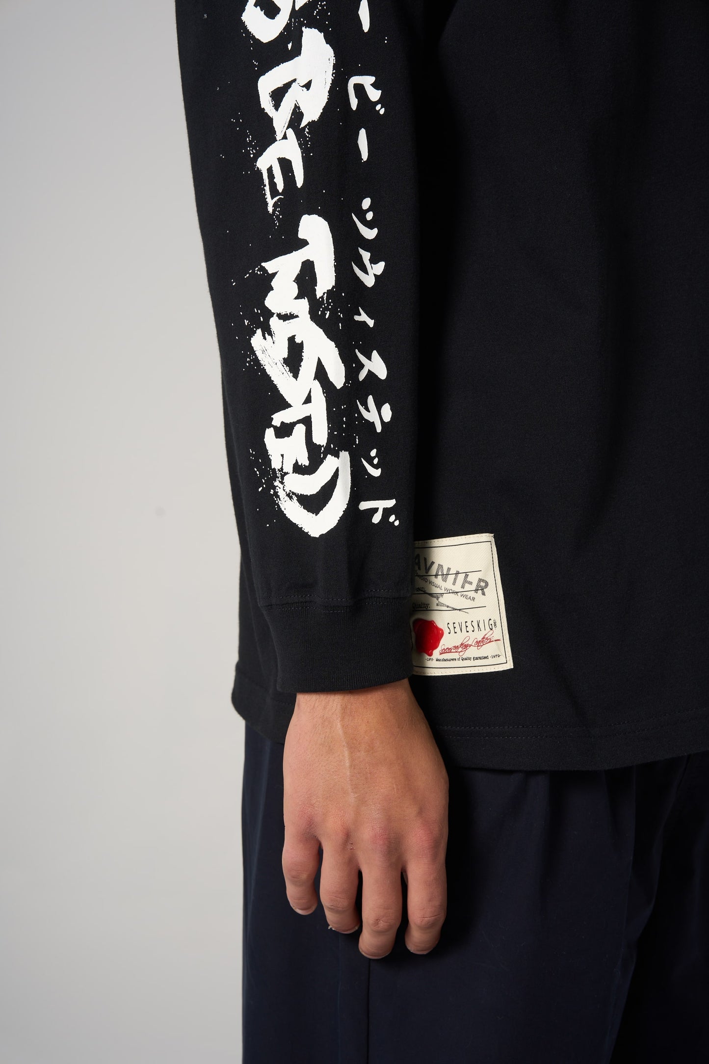 Détail sur la manche du t-shirt noir AVNIER × SEVESKIG, lettrage graphique inspiré du style japonais. - noir
