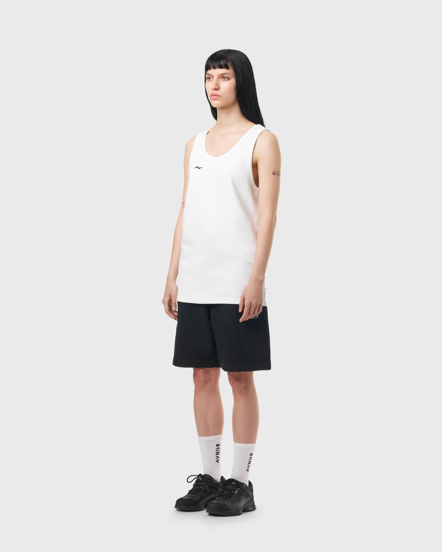 Débardeur blanc Avnier Aperture porté par une femme, vue de profil, coupe droite et style décontracté.