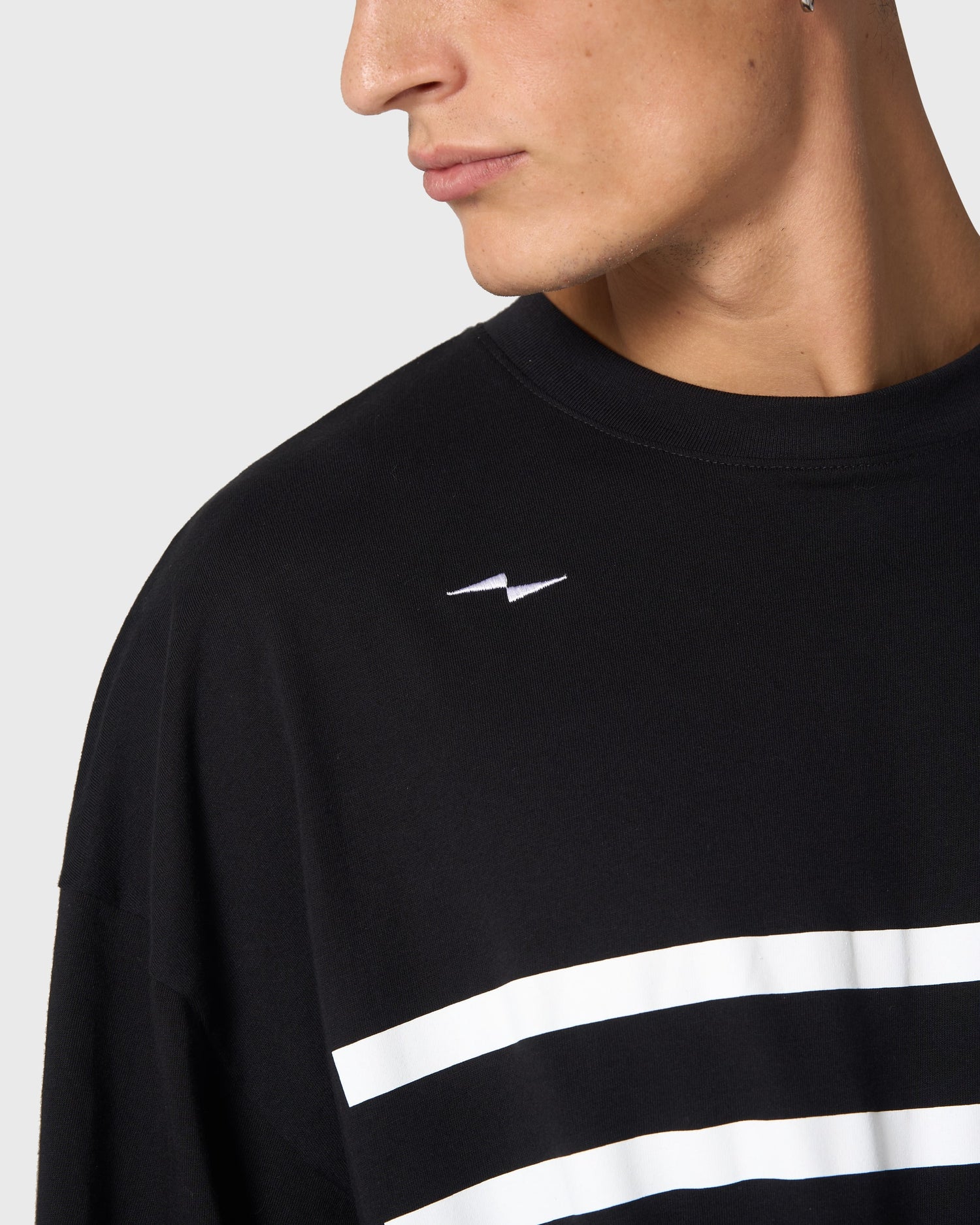 Zoom sur le logo AVNIER brodé à l’épaule du t-shirt Yocaen noir, détail de finition premium.