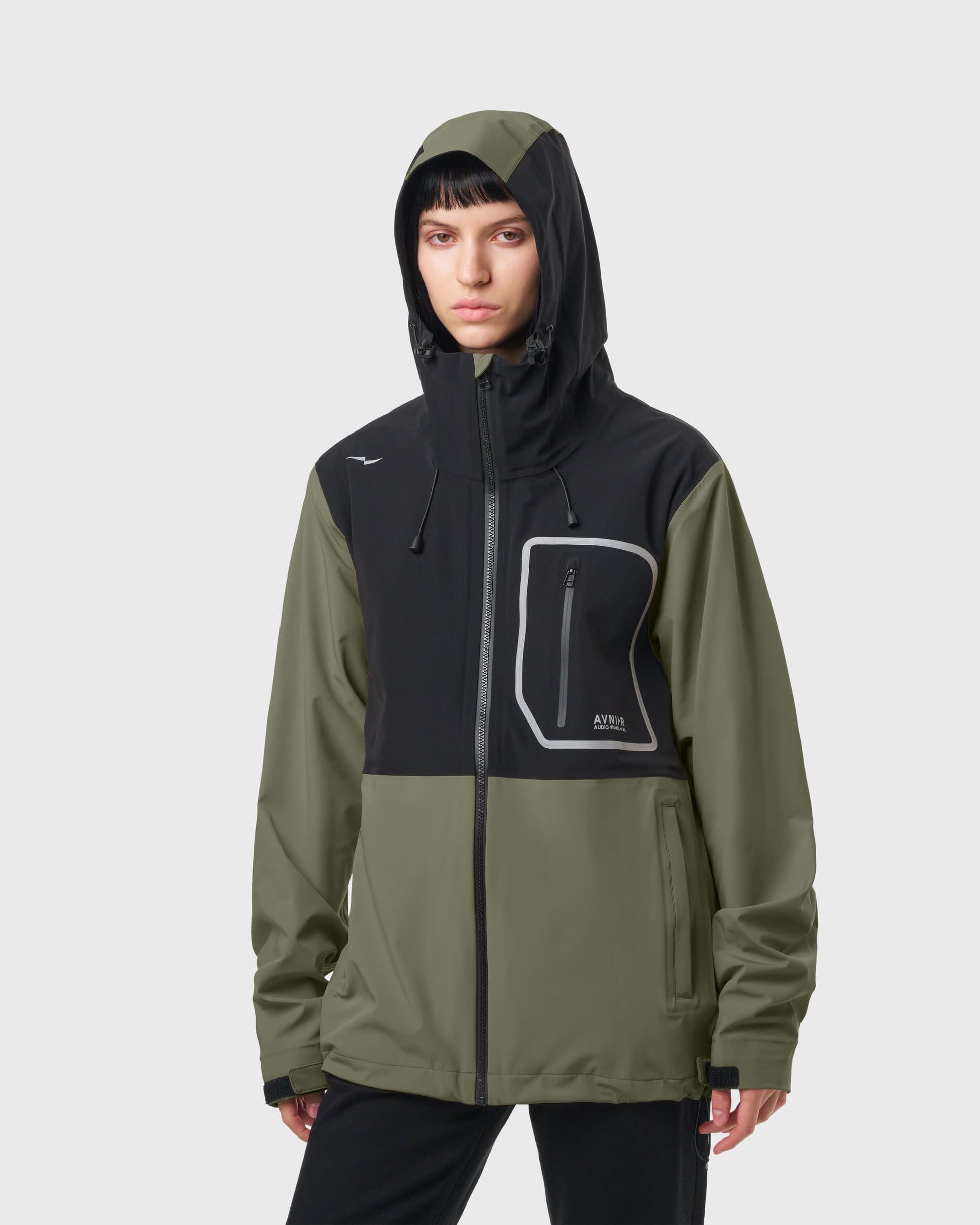 Veste Avnier Hardshell Interlude kaki portée par une femme, style workwear fonctionnel, coupe droite avec capuche réglable. - kaki