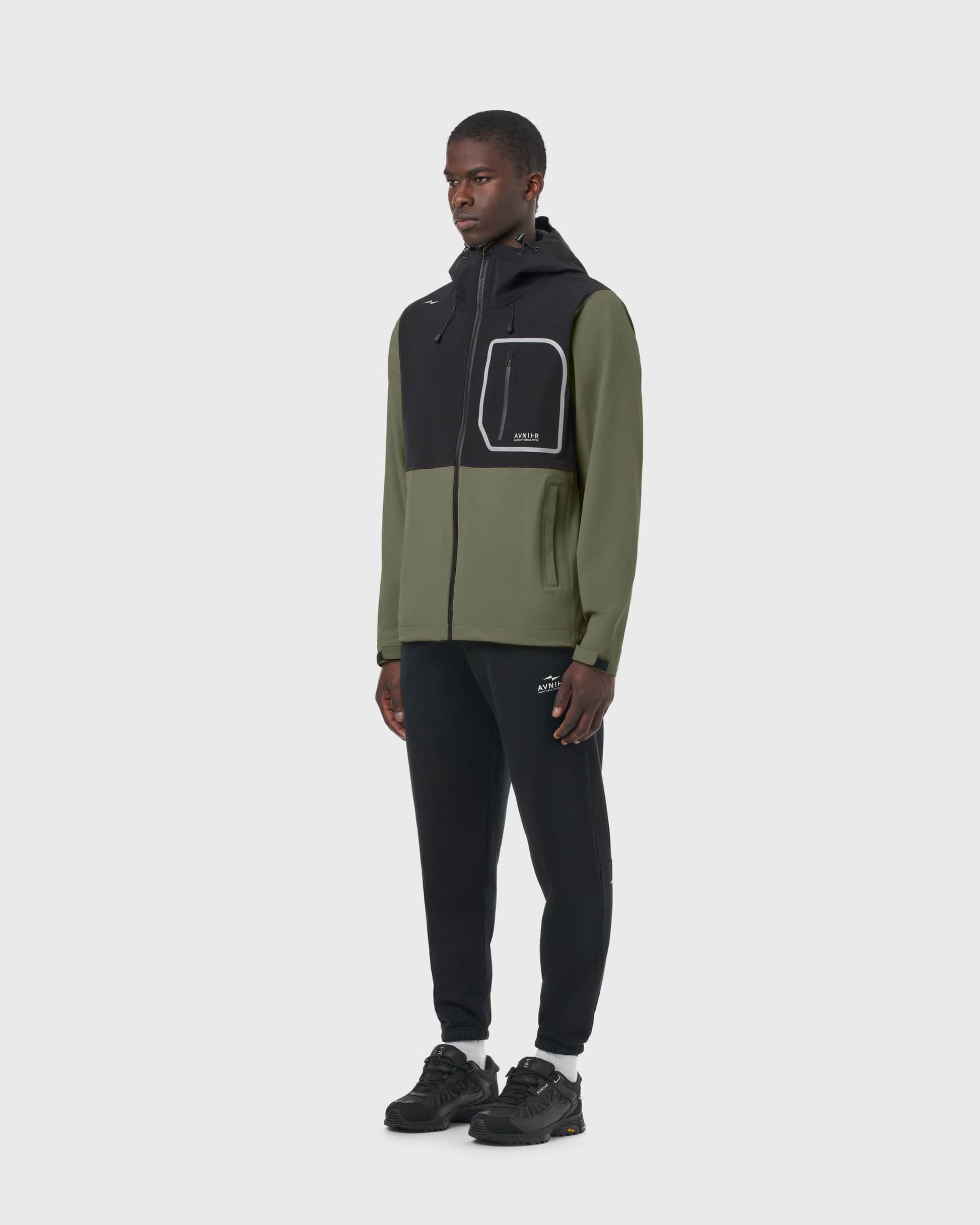 Veste AVNIER Interlude kaki et noire portée par un homme de profil, coupe imperméable technique. - kaki